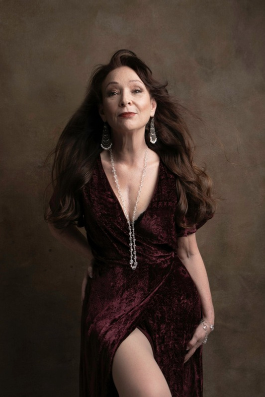 Portrait of a woman with long dark hair in a burgundy velvet gown